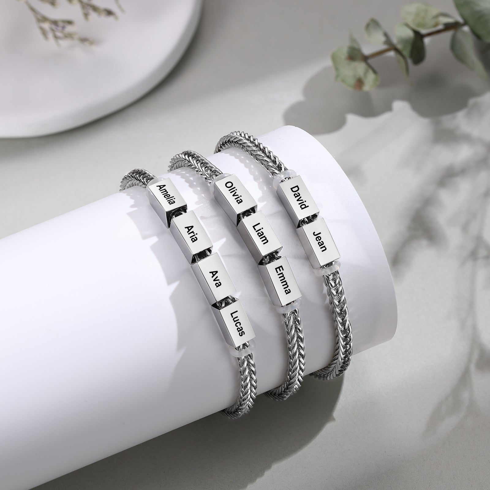 Three silver wheat-chain family bracelets with two, three, and four engraved name charms shown side by side